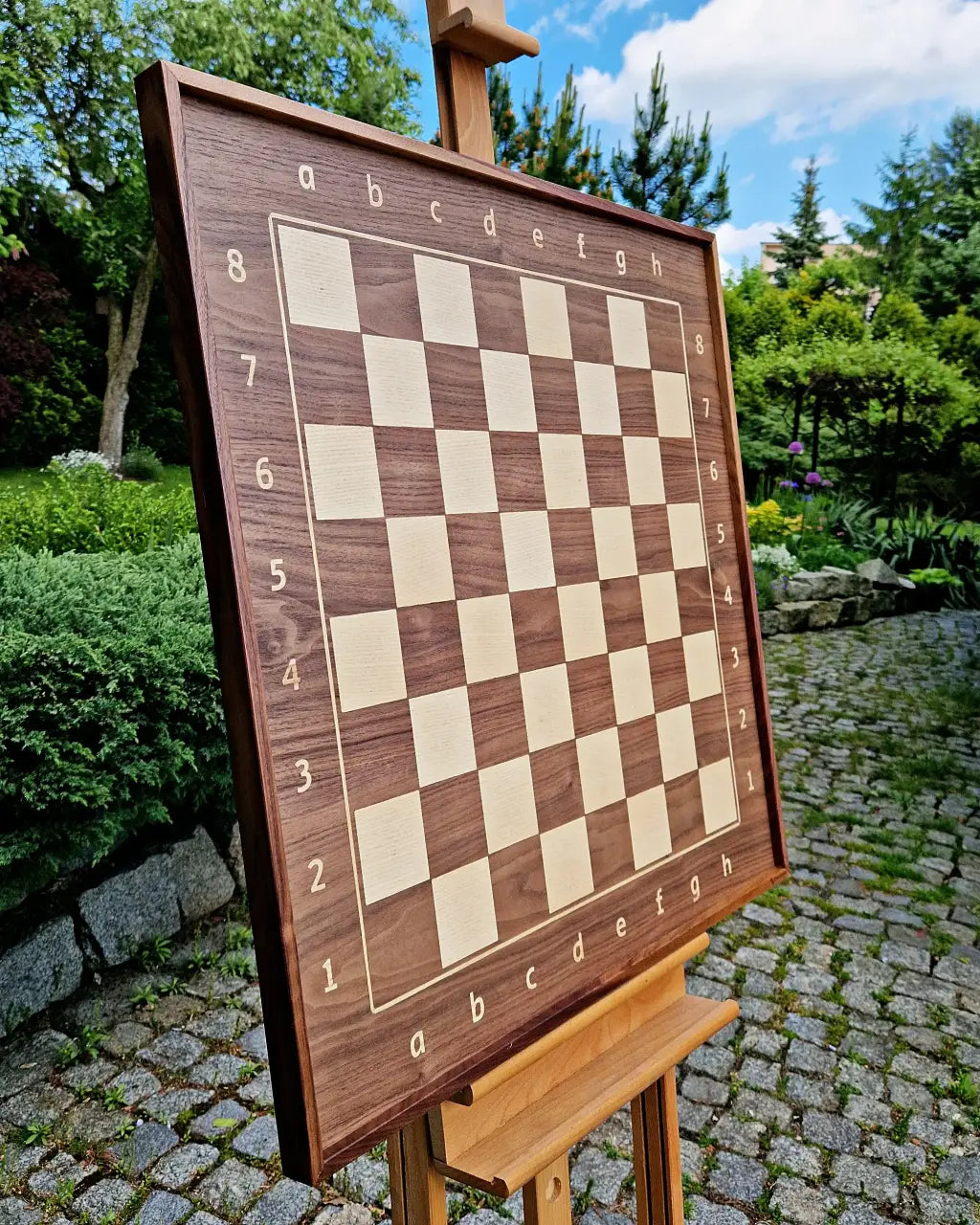 Premium wall-mounted chess board by ChessboArt in American Walnut and Ash. Elegantly displayed outdoors.