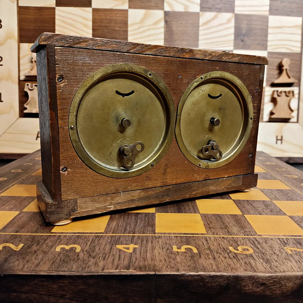 Back view of the antique HAU mechanical chess clock showing the original winding keys, setting knobs, and the aged wooden back panel.