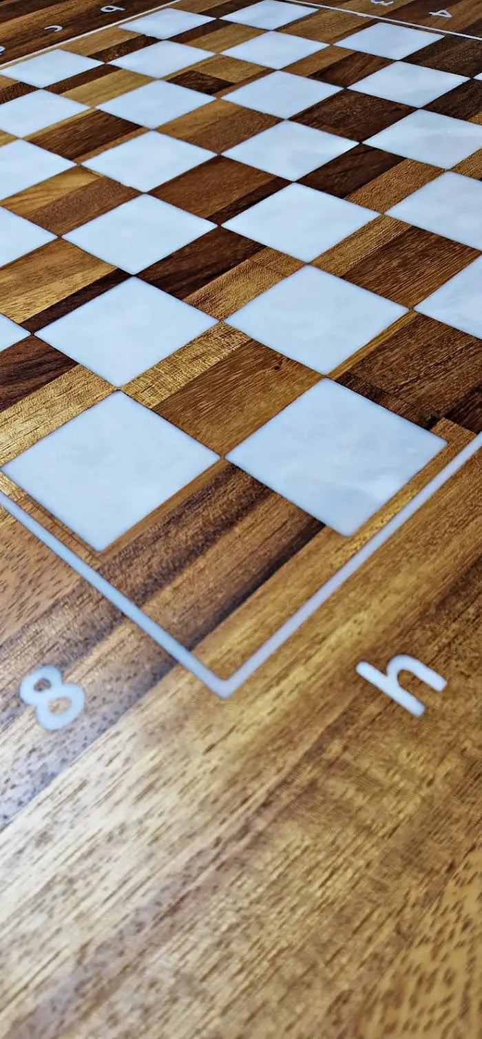 A close-up detail shot of the h8 corner of a ChessboArt bughouse chess table, showcasing the rich, distinct grain of the exotic Iroko wood.