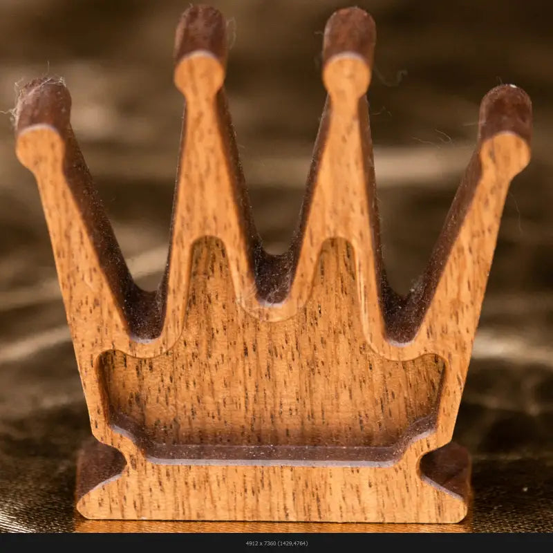 Close-up detail of a handcrafted wooden chess queen on a dark reflective surface, fine art photography by Monika Burszczan