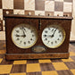 Front view of an ultra rare antique HAU chess clock in a solid wood case. Note the unique dial design without falling flags and the visible crack on the front panel.